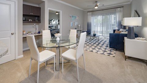 a dining room and living room with a glass table and white chairs